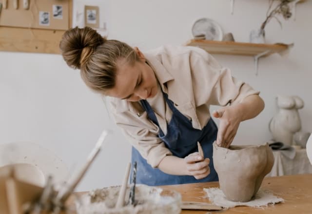 Vrouw die bezig is om haar keramiek in de goeie vorm te krijgen