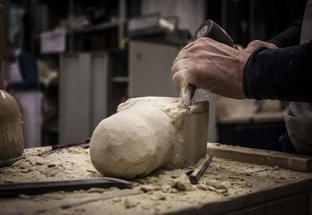 iemand aan het beeldhouwen met een hamer