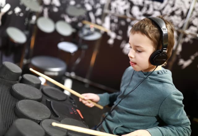 Jongen met koptelefoon speelt drums