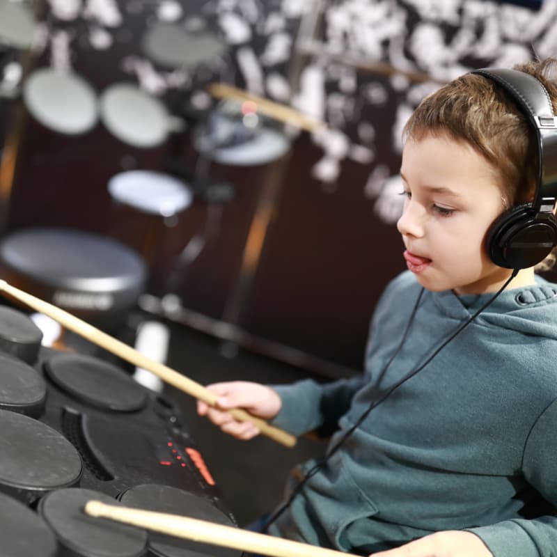 Jongen met koptelefoon speelt drums