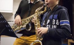 Saxofoon, docent kijkt naar kind die aan het spelen is